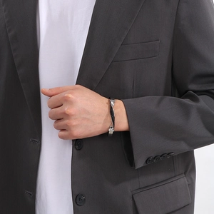 Detail of men's twisted black leather and stainless steel bracelet on a wrist