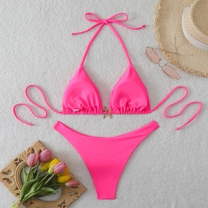 Flat lay of pink halter bikini with gold starfish detail on white faux fur background
