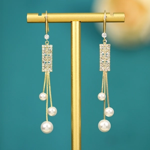 Detail of long gold tassel earrings with micro-pave crystals and hanging white pearls