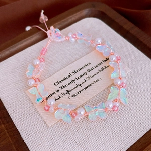 Macro view of butterfly bead and pearl charm bracelet with adjustable pink cord