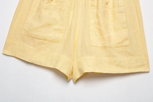 Detailed close-up of yellow linen shorts featuring large pockets and premium stitching