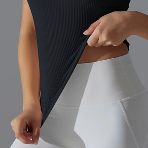 Gros plan sur la texture du débardeur de yoga noir côtelé et les coutures du legging blanc