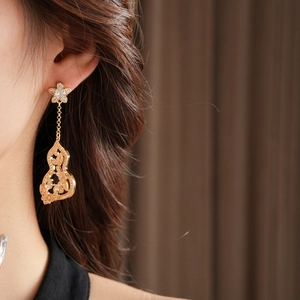 Gros plan de boucles d'oreilles fleur et gourde dorées avec glands en zircone sur modèle