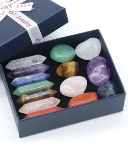 Macro view of 16 assorted natural crystal pillars and tumbled stones in a blue gift box