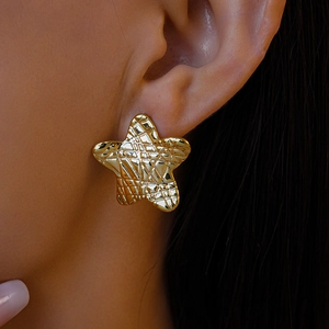 Gros plan de boucles d'oreilles étoile dorées texturées portées par un mannequin élégant
