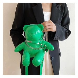 Detail of a bright green bear-shaped PU leather crossbody bag with silver chain straps