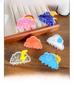 Close-up of acrylic weather-themed hair claws with rhinestones on a wooden tray