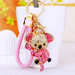 Detail eines Kristall-Koala-Schlüsselanhängers mit rosa Webband an einer Teetasse