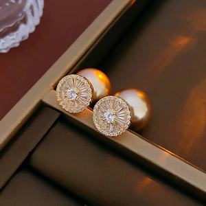 Détail macro de boucles d'oreilles perles dorées avec zircons radiants sur un présentoir