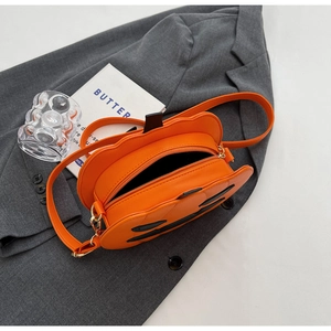Detail showing the festive orange pumpkin crossbody bag with black face and long strap