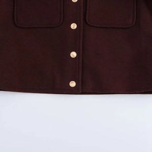 Détail de la texture en laine de la veste bordeaux avec boutons dorés et poches