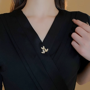 Detail of elegant gold butterfly brooch with mother of pearl and zircon on black dress