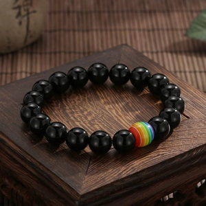 Dettaglio del bracciale in pietra lavica nera con perla arcobaleno su base di legno