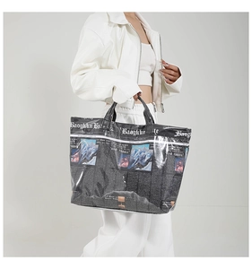 Detail van een grote shopper met krantenprint en zwarte versterkte handvatten