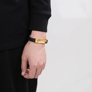 Detail of black woven leather bracelet for men featuring a gold geometric magnetic clasp