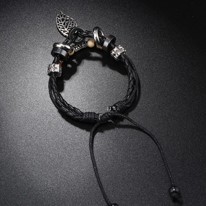 Detail of multilayer beaded leather bracelet with leaf pendant and skull charm