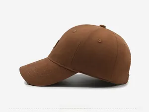 Side view of brown cotton baseball cap showing circular logo patch and neat stitching