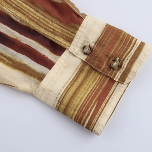 Détail du poignet d'une chemise rayée avec boutons marrons et coutures précises
