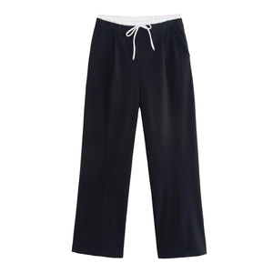 Detail of high-waist wide-leg pants featuring a black body and white drawstring waistband