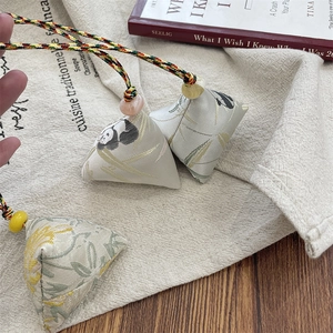 Three embroidered Zongzi charms with panda patterns on rustic wooden background