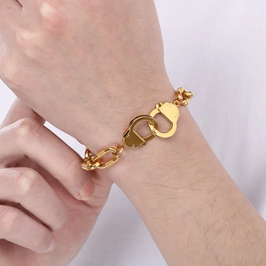 Close-up of gold handcuff clasp bracelet on wrist with industrial link chain detail