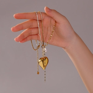 18k gold plated necklace with heart pendant, pearl and rhinestones held by hand