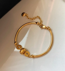 Detailed macro of 18K gold plated bamboo bracelet with EMMA charm and lobster clasp