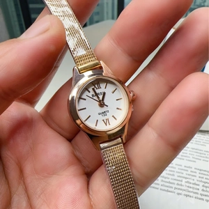 Elegant gold mesh strap watch with a small white dial and minimalist roman numerals