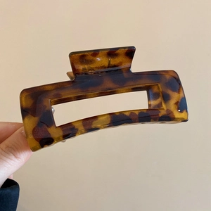 Detail of a large rectangular amber leopard print hair claw clip with a glossy resin finish