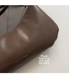 Macro detail of brown matte leather texture and embossed logo on the commuter bag