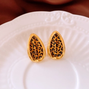 Macro view of teardrop stud earrings with 24k gold plating and leopard print patterns