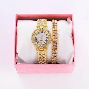 Close-up of gold iced-out watch and diamond bracelet set in a pink gift box