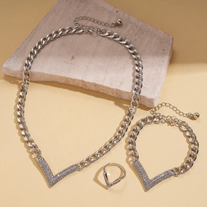 Close-up of silver-toned V-shaped jewelry set with necklace, bracelet, and ring on stone