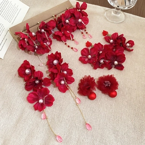 Detailed view of red fabric flower earrings with crystal tassels and pearl centers