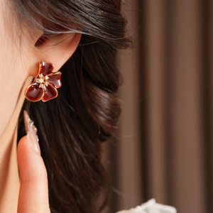 Close-up of vintage red enamel flower earring with gold edge and zircon center on ear