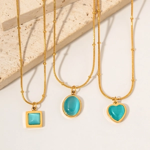 Detailed view of three gold necklaces with square, oval, and heart-shaped blue stones