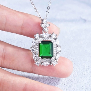 Detailed view of emerald-cut green gemstone pendant with micro-pave diamonds on silver