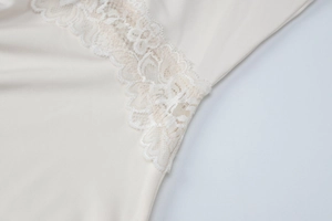 Detail shot of delicate beige lace trim and soft fabric texture on a V-neck dress