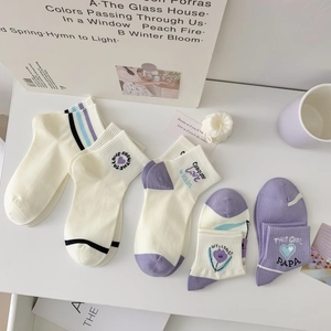 Gros plan de cinq paires de chaussettes en coton avec broderies de fleurs et cœurs mauves