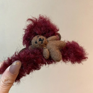Detailed view of a plush burgundy hair claw clip featuring a cute brown flocked bear ornament