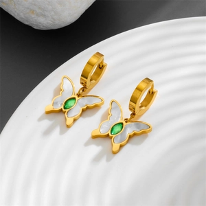 Golden butterfly earrings with green zircon and white shell inlay on a white display tray