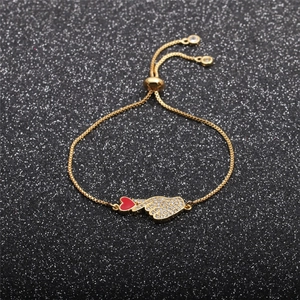 Detail of adjustable gold bracelet featuring a red enamel heart and zircon hand charm