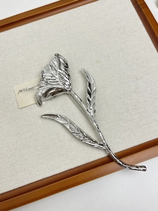 Close-up of silver tulip flower brooch with detailed metallic texture and elegant curves