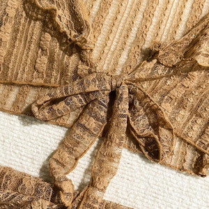 Close-up of brown floral lace swim cover-up with delicate front bow tie detail