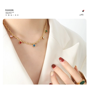Detailed shot of gold twisted chain necklace featuring five vibrant heart-shaped gemstones