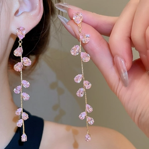 Macro detail of elegant golden tassel earrings featuring delicate pink pear-shaped gemstones