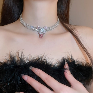 Detail of silver choker necklace with pearls, rhinestones and pink bow pendant on model