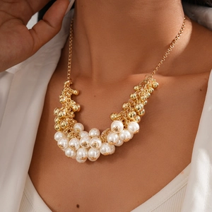 Detailed view of Baroque pearl and gold bead cluster pendant on an elegant long necklace