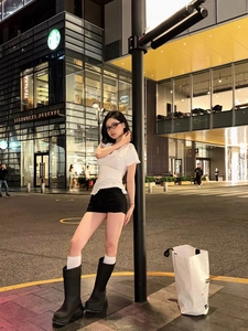 Slim fit white V-neck short sleeve T-shirt styled with black high-waisted shorts and boots