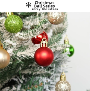 Close-up of decorative red and green Christmas balls hanging on a snowy Christmas tree